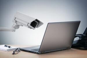 Laptop computer being watched in the office by a security camera concept for big brother surveillance or internet computer security