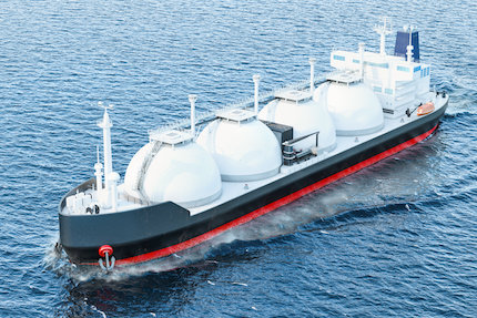 Tanker sailing in ocean with LNG tanks on ship with sky background.