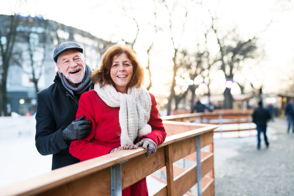 Older couple posing for a photo in a snowy park.