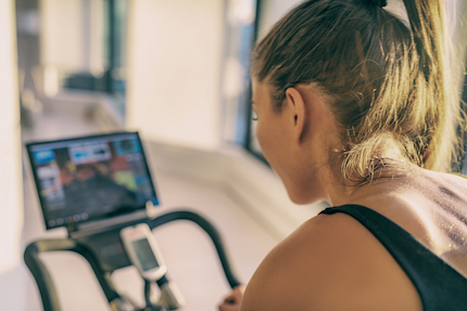 Young woman on exercise bicycle with video monitor.