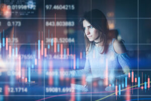 Young woman traider working at night modern office.Technical price graph and indicator, red and green candlestick chart and stock trading computer screen background. Double exposure