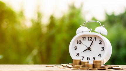 Alarm clock and gold coins on a table.