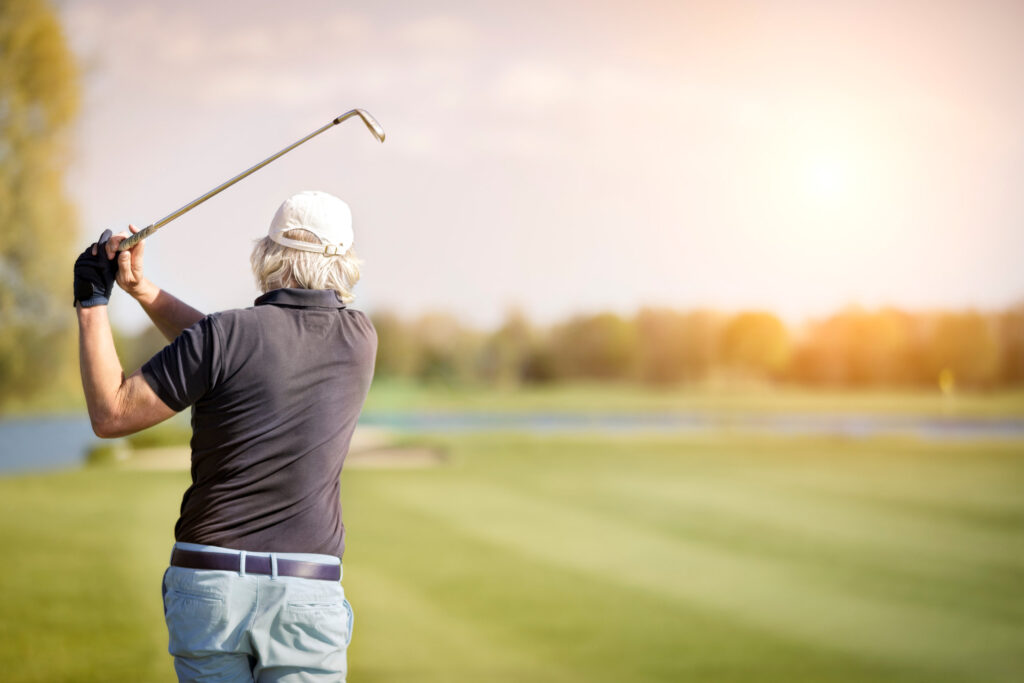 Man hitting a golf ball on a golf course.