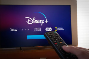 Barcelona, Spain. Jan 2019: Man holds a remote control With Netflix, HBO and the new Disney+ logos on TV screen. Disney+ is an online video streaming subscription service, set to launch in the US in September.Illustrative editorial