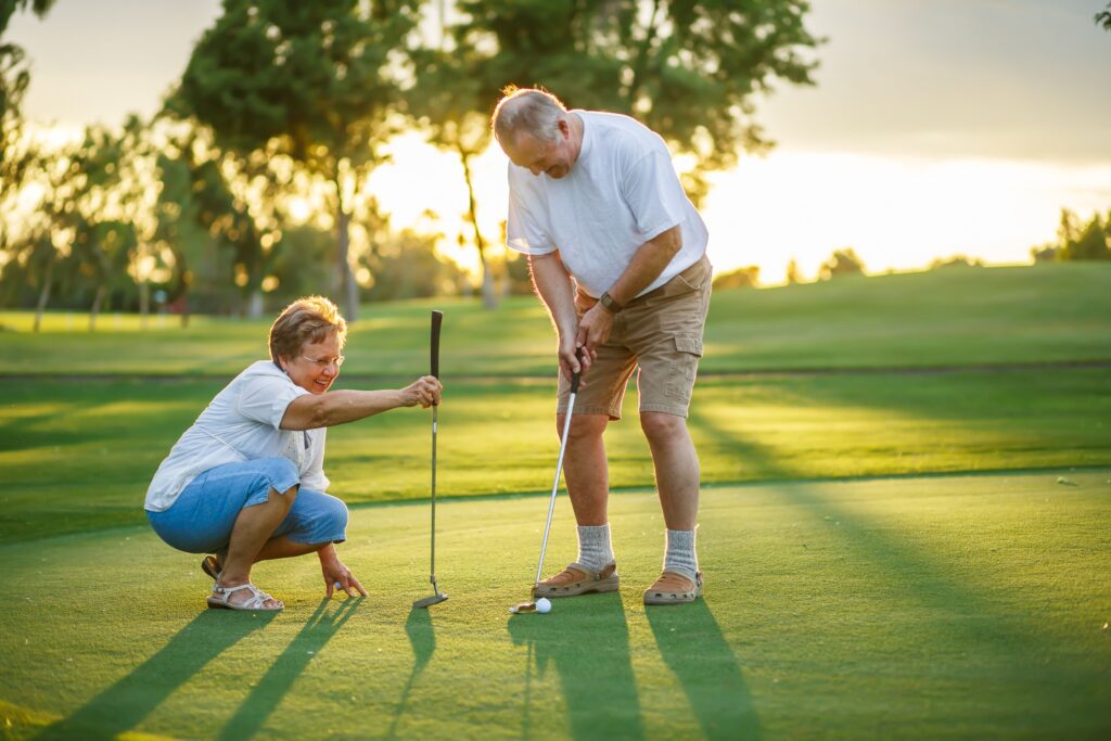 Two people playing golf at sunset.