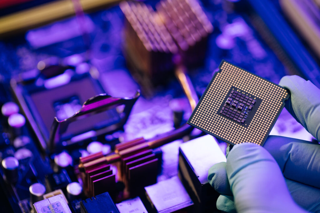 Engineer showing a computer microchip on motherboard background. Electronic circuit board with processor