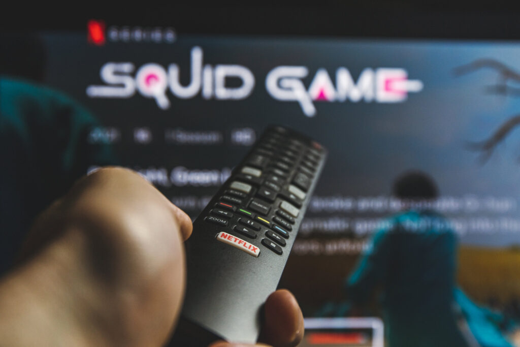 Person pointing a remote at a TV that has Squid Game playing.