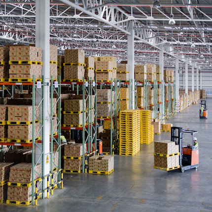 Inside a modern logistics warehouse showing goods on a palette being moved by a forklift.
