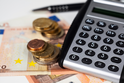 Coins sitting on top of paper money next to a calculator.