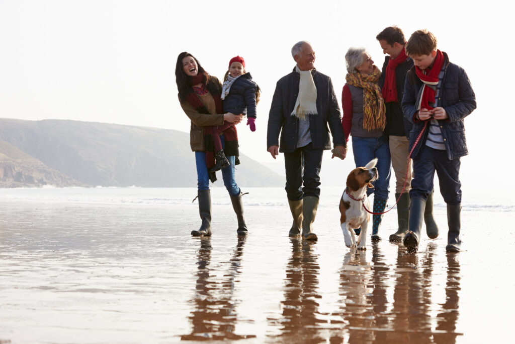 Family of six with their dog walking on a beach.