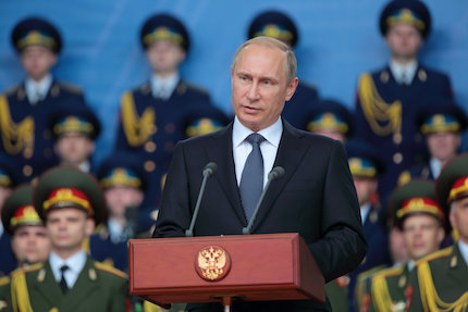 Picture of Vladimir Putin giving a speech in front of uniformed military personnel.