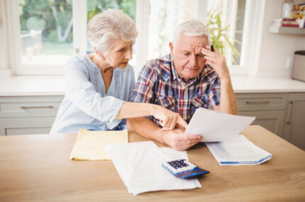 Worried senior couple checking their bills at home