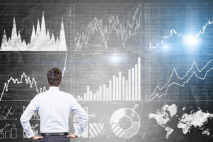 Research concept with businessman looking at forex charts on dark grey concrete wall