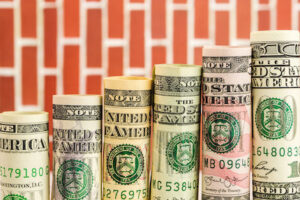 rising steps made of rolls of all american dollar banknotes in one row on red wall background