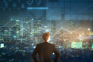 73769117 - back view of young businessman looking into the distance on night city and forex chart background. trading concept