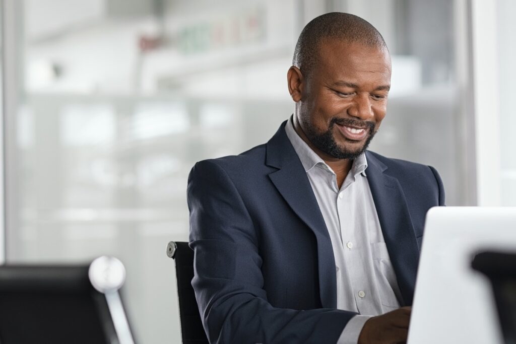 Portfolio diversification: Businessman smiles while typing on his computer