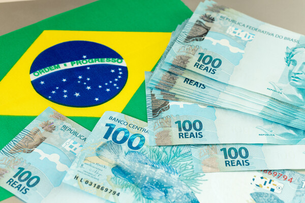 Brazilian money banknotes on the background of the flag of the country