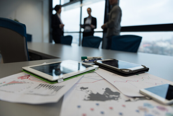 Close up of smart phone on table in boardroom with business people in the background