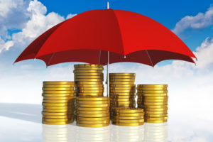 Financial stability, business success and insurance concept: stacked golden coins covered by red umbrella against blue sky with clouds on white background with reflection effect