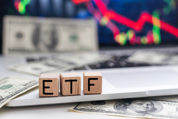 ETF written on blocks on a background of money and a computer