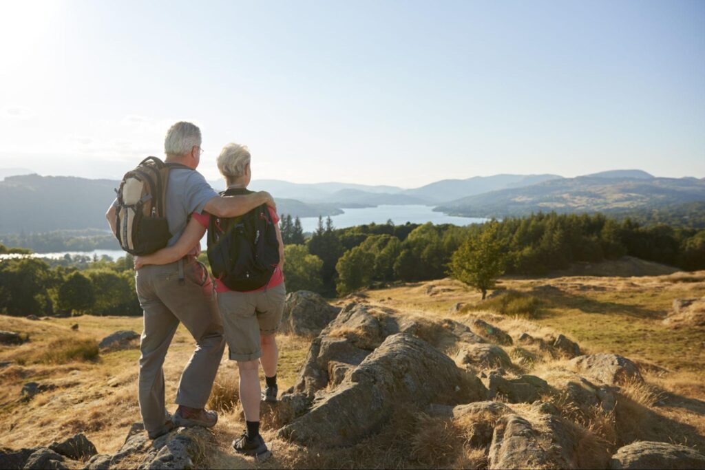best investments for retirement: Elderly couple enjoying the view on top of a mountain