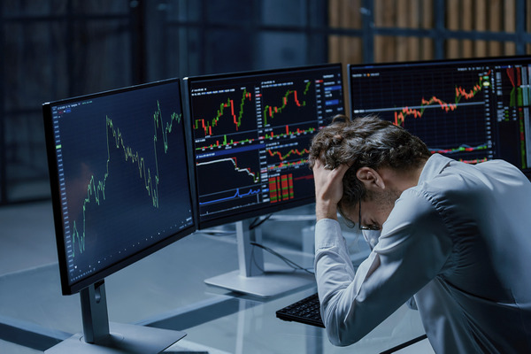Frustrated investor sitting in front of trading screens