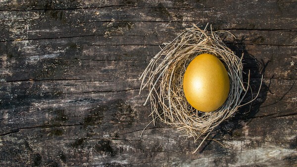 Golden egg in a nest on a wooden surface