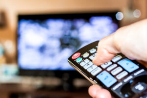 Hand hold the remote control to change channels on Television