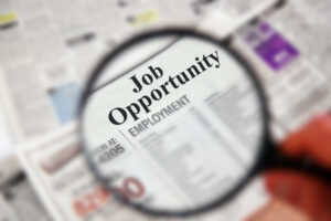 Magnifying glass over a newspaper classified section with  Job Opportunity  text