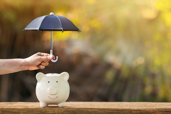 covered calls for income: Person holding a small umbrella over a piggy bank