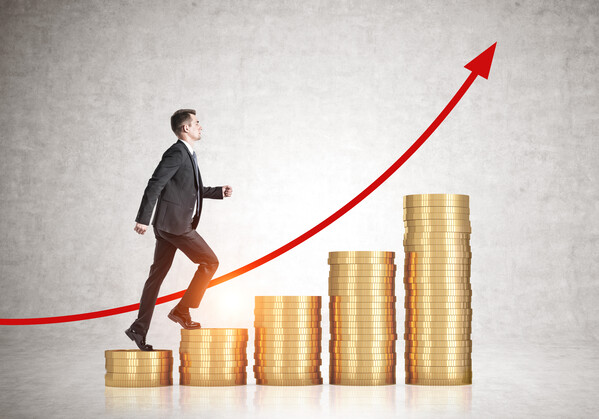 Side view of young businessman climbing stacks of coins in concrete room - concept of financial success and career growth