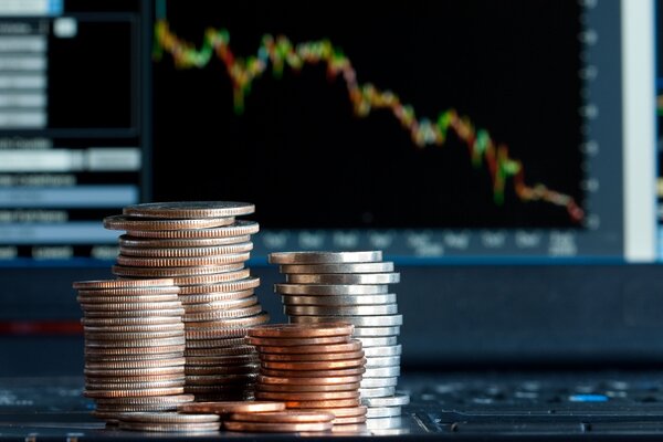 Stacks of coins in front of a stock chart