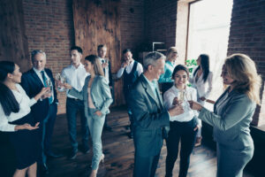 Close up photo business people crowd different age race leisure excited team building members gathering she her he him his golden wine beverage say toasts congrats formal wear jackets shirts.
