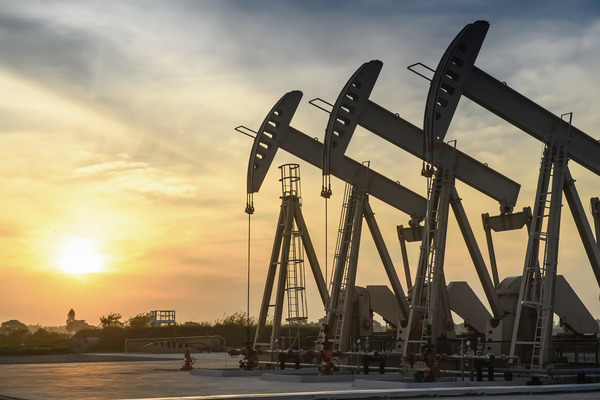 Three oil pumpjacks against a rising sun