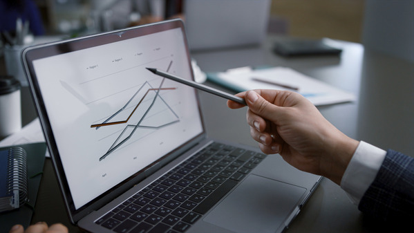 Trader pointing at financial graph on laptop