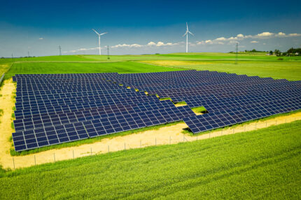 View of solar panels and wind turbines in field