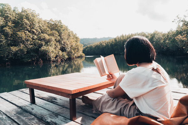 Woman reading book alone on pier