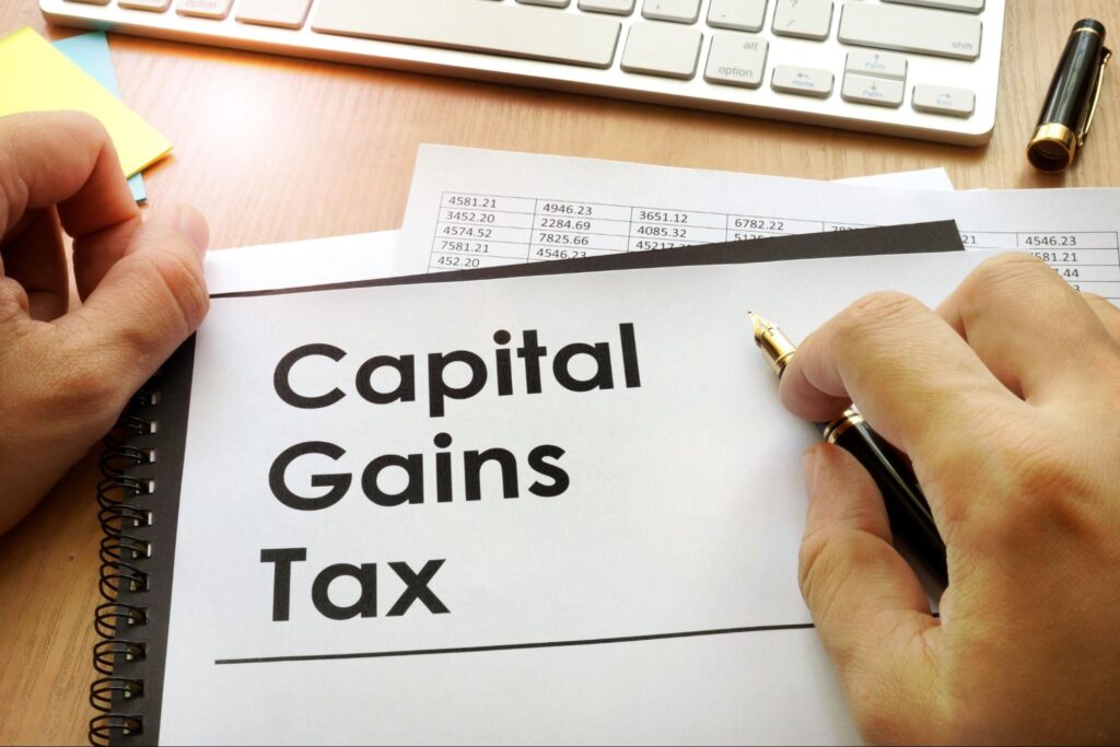 man holding a pen and a notebook with capital gains tax