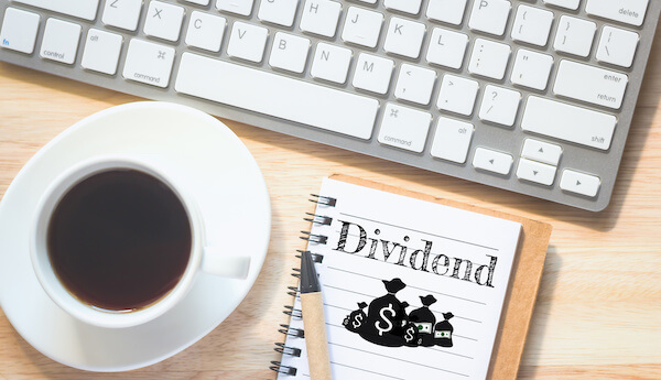 What are dividends: Dividend written on a notebook beside a cup coffee and a keyboard