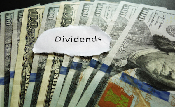 Dividend investing strategy: dividends written on a piece of paper on top of cash