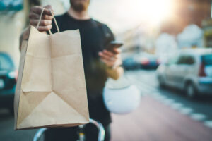 Anonimous fast delivery food service at home. Man courier delivered the order no name bag with food.