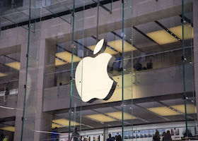 Glowing Apple logo attached to the top of an Apple Store.