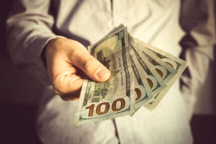 Five $100 bills in a man's hand