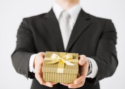 Man reaching out to hand someone a present in gold wrappoing.