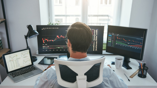 Traders guide: guy looking at multiple monitor