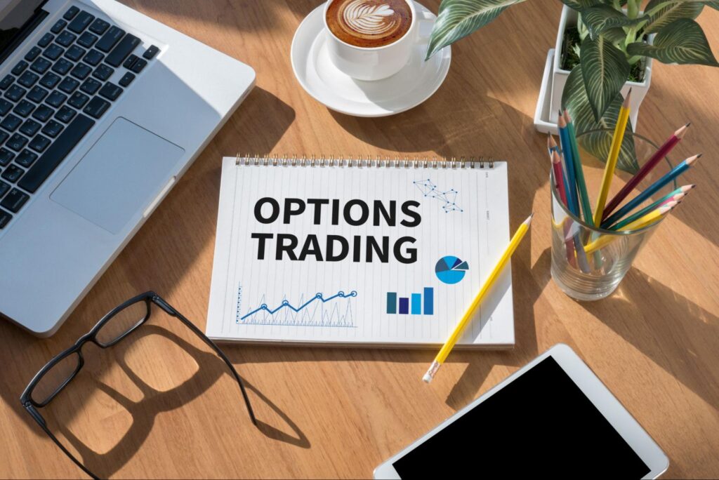 how to trade options: options trading in a notebook with laptop, cellphone, coffee, and pencils