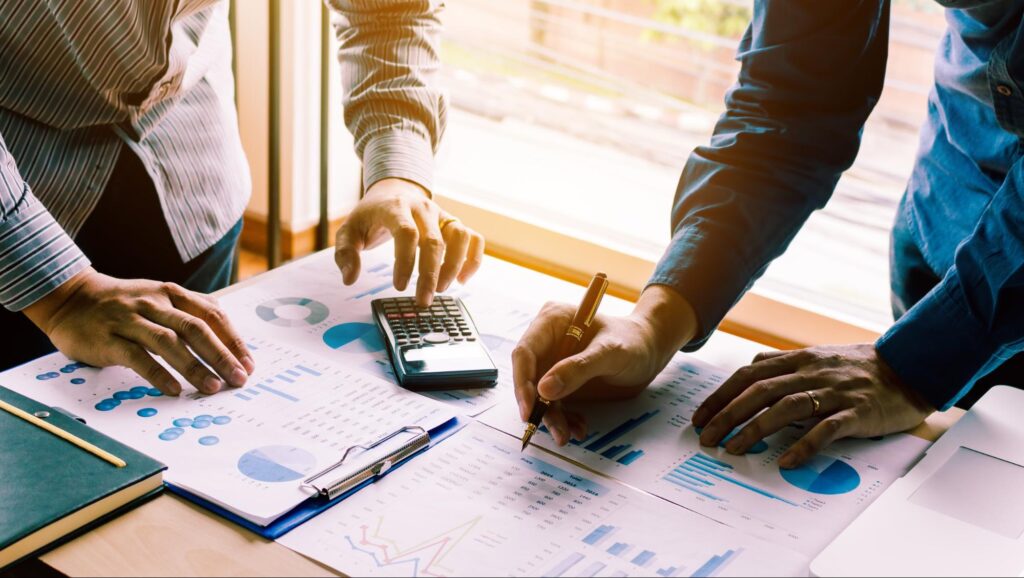 high yield investments: man holding a pen and another man using a calculator