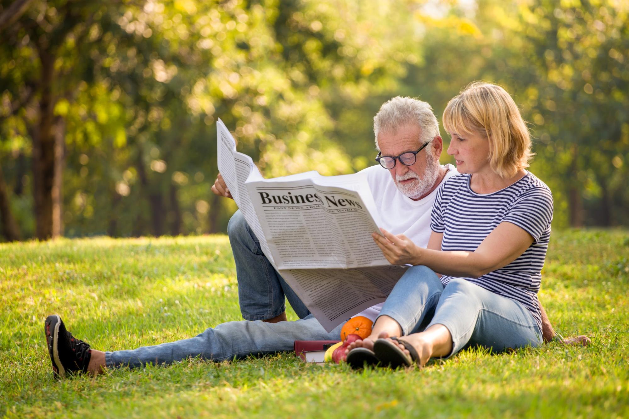 dividend investing: old man and woman reading a newspaper outside