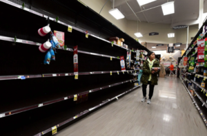 Woman walks down an empty aisle at the supermarket due to supply chain issues. 