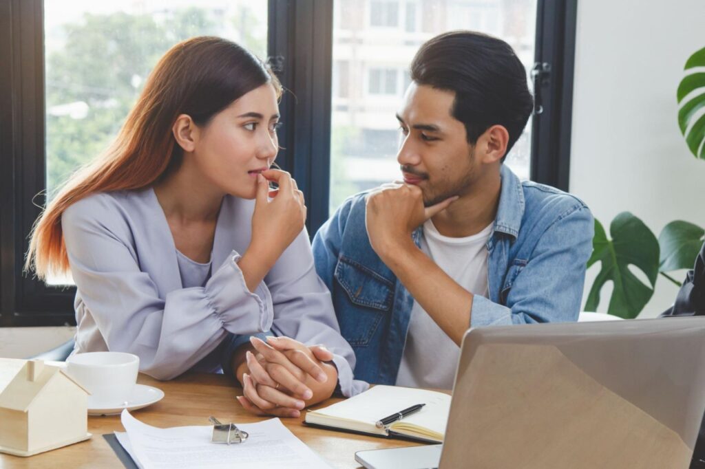 real estate stocks: Young couple holding hands while looking at each other